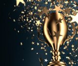 A gold trophy on a very dark blue background with flying golden stars