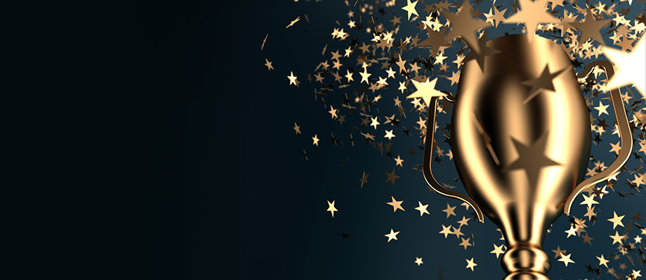 A gold trophy on a very dark blue background with flying golden stars