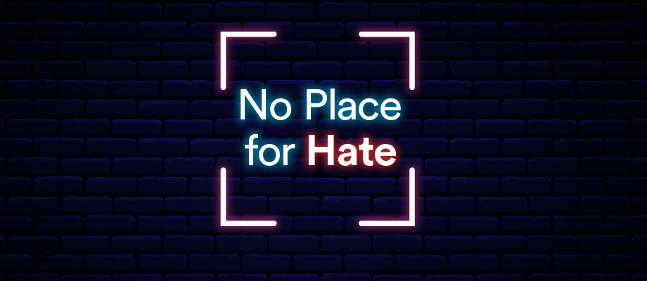 'No Place for Hate' neon text on a blue brick background